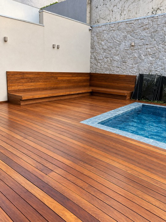Deck de madeira com banco embutido ao redor de piscina